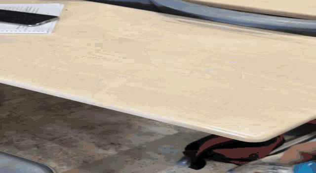 a cell phone sits on a desk next to a piece of paper