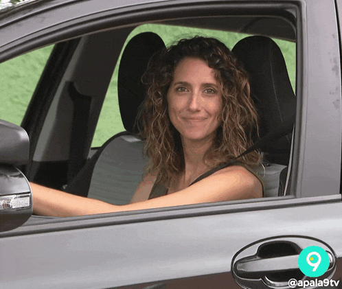 a woman is sitting in a car with the number 9 on the door handle