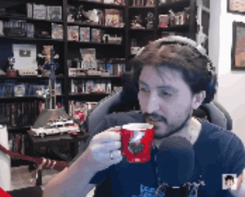 a man wearing headphones is holding a red cup in front of a microphone