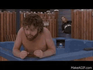 a shirtless man with a beard is laying in a blue hot tub .