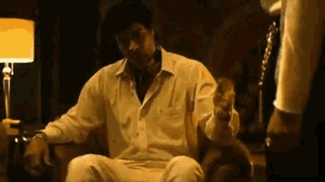 a man is sitting in a chair in a dark room with a lamp .