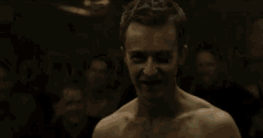 two men without shirts are fighting in front of a crowd with one wearing a shirt that says ' snoop dogg '
