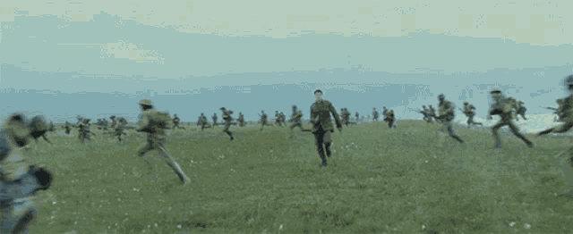 a group of soldiers are running in a field while an explosion takes place .