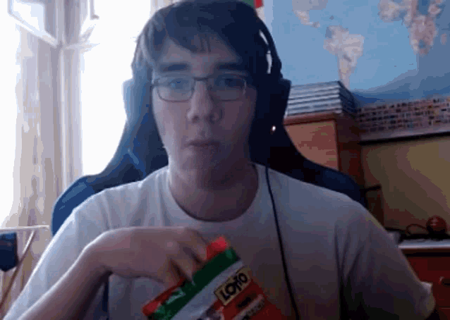 a man wearing glasses and headphones is eating a bag of loro chips