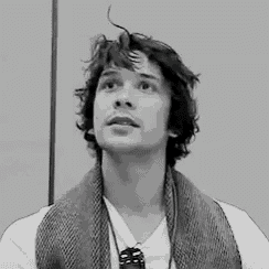 a black and white photo of a young man with a scarf around his neck
