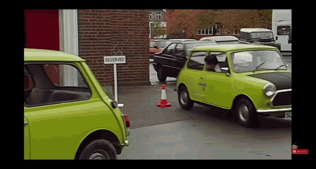 two green cars parked next to a reserved sign
