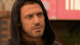 a man with a beard wearing a hooded sweatshirt looks at the camera .