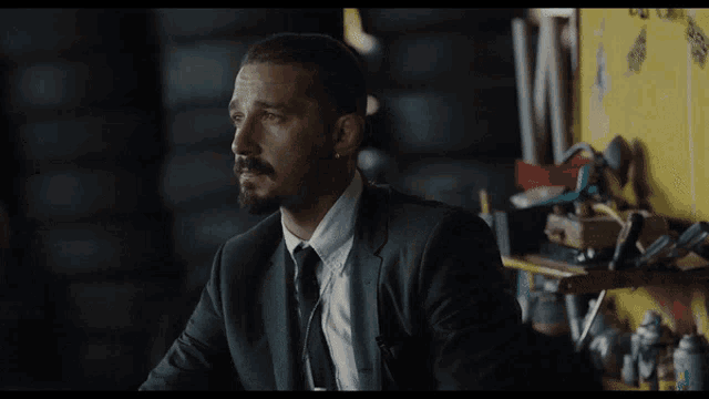 a man in a suit and tie is sitting in a dark room
