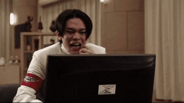 a man with a red armband on his arm is looking at a computer monitor