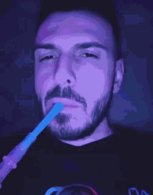 a man with a beard is smoking a hookah in front of a colorful background .
