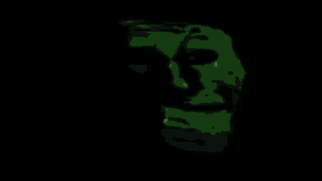 a green troll face with a black background is glowing in the dark .