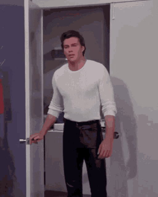 a man in a white shirt and black pants is standing in a doorway .