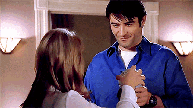 a man in a blue shirt holds a woman 's hand