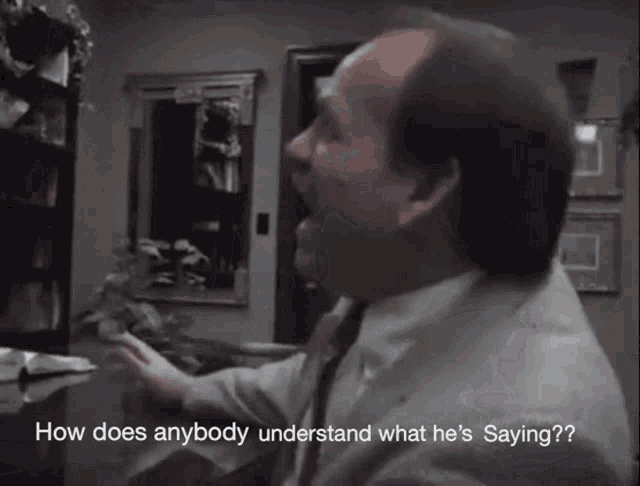 a man in a suit and tie says how does anybody understand what he is saying