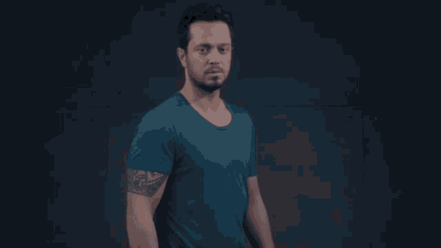 a man in a blue shirt with a tattoo on his arm
