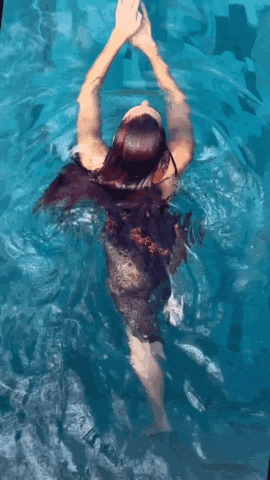 a woman swimming in a pool with her arms outstretched
