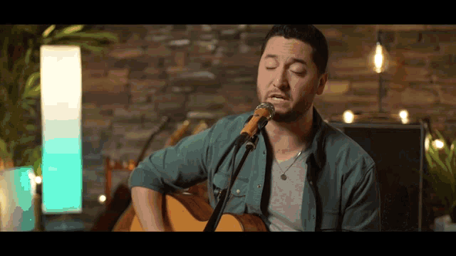 a man is singing into a microphone while playing an acoustic guitar