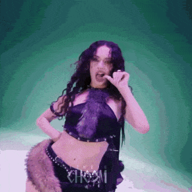 a woman in a purple fur crop top and shorts is eating a piece of food .