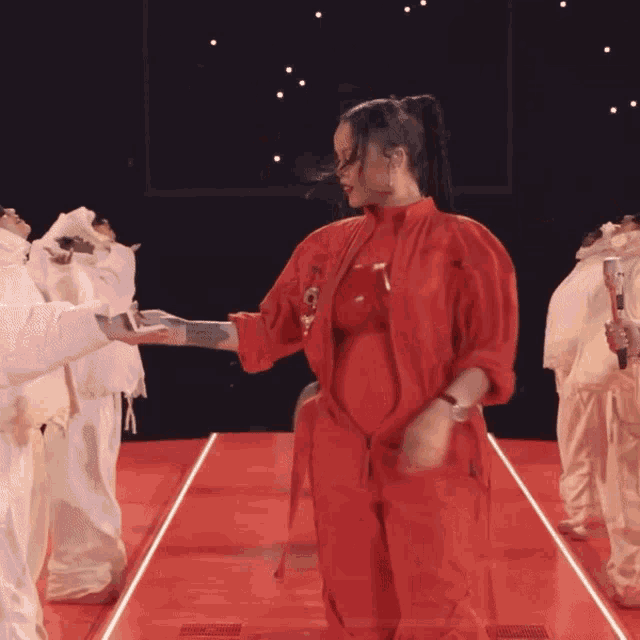 a woman in a red outfit is dancing in front of a group of people