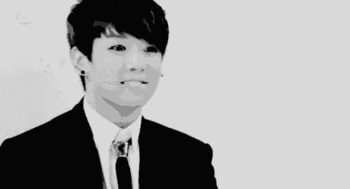 a young man in a suit and tie is making a funny face in a black and white photo .