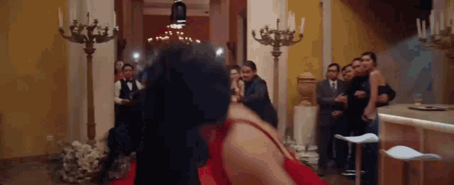 a woman in a red dress is dancing on a red carpet in a room .