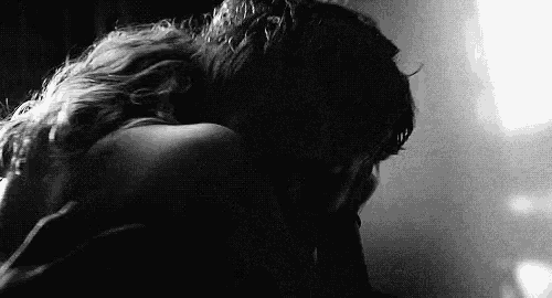 a black and white photo of a man and a woman hugging each other .