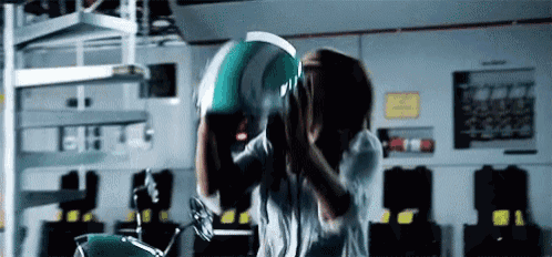 a man is holding a green helmet over his head in a garage .