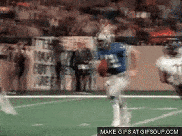 a football player in a blue uniform is running with the ball on a field