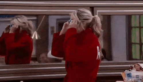a woman in a red robe is looking at herself in a mirror .