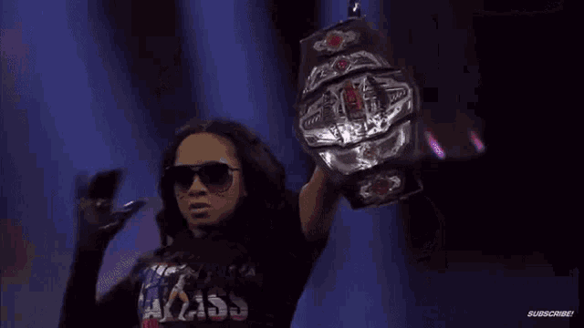 a woman is holding a wrestling championship belt in a dark room .