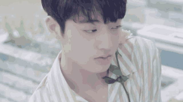a young man in a striped shirt is holding a flower