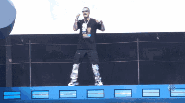 a man wearing a shirt that says ' simpson ' on it stands on a stage holding a microphone