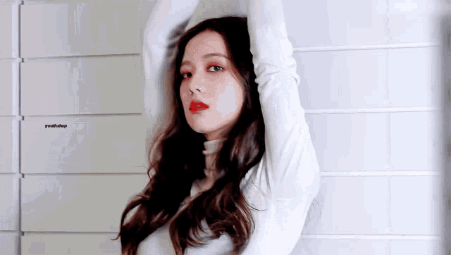 a woman with long hair and red lips is wearing a white turtleneck sweater and red lipstick .