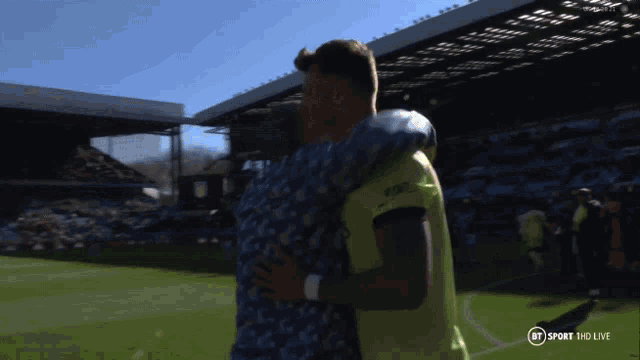 two men hugging on a soccer field with bt sport hd live on the bottom right