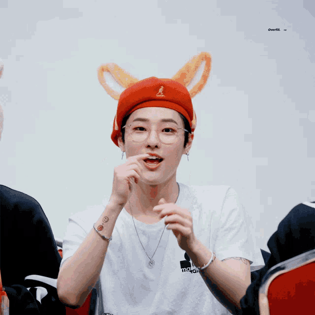 a young man wearing a red hat with kangaroo ears on it