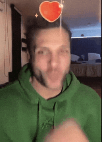 a man wearing a green hoodie with a heart on his head