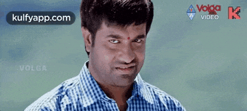 a man in a blue and white checkered shirt is smiling with his eyes closed in a video .