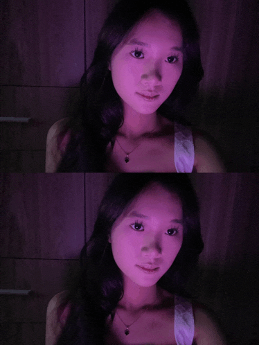 a woman 's face is shown in purple light and in a dark room