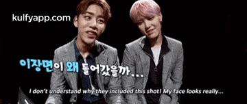 two young men are sitting next to each other on a black background and talking to each other .