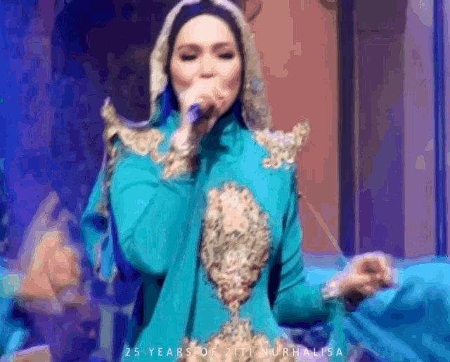 a woman in a blue dress singing into a microphone with the words 25 years of ziti murhalisa written below her
