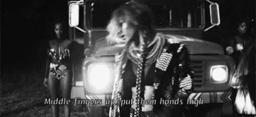 a black and white photo of a woman standing in front of a truck with the words middle fingers up put them hands high .