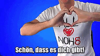 a man making a heart shape with his hands in front of a blue background