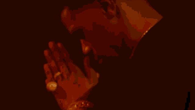 a man is praying with his hands folded in a dark room