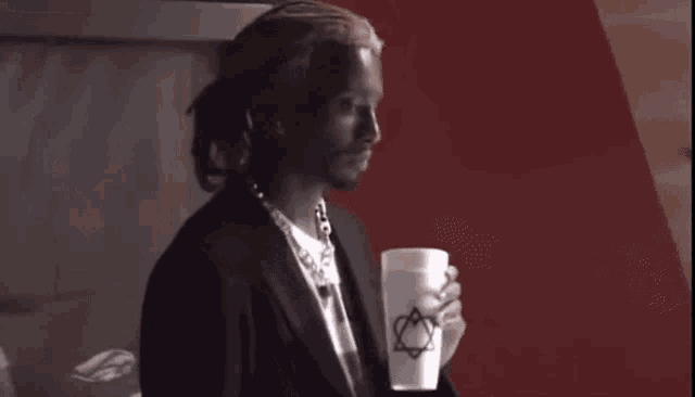 a man is holding a cup of coffee in his hand .