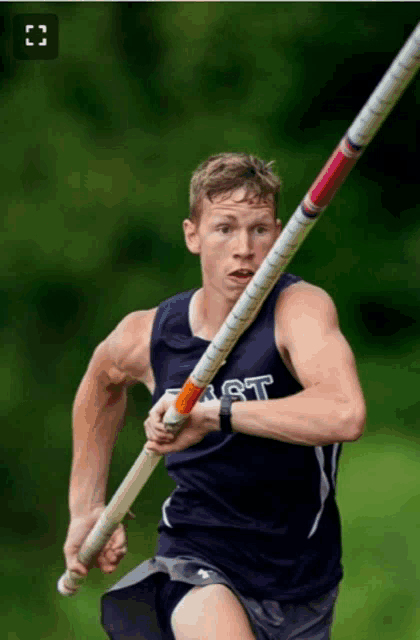 a man wearing a vest that says east is running with a pole