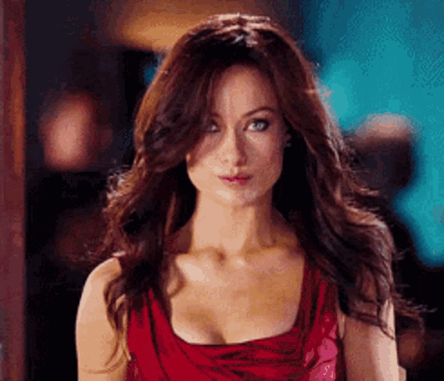 a woman in a red dress looks at the camera with a serious look on her face