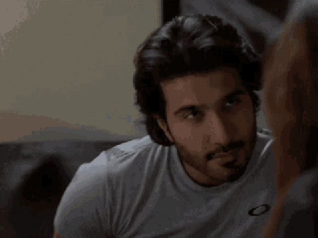 a man with a beard is wearing a grey oakley shirt