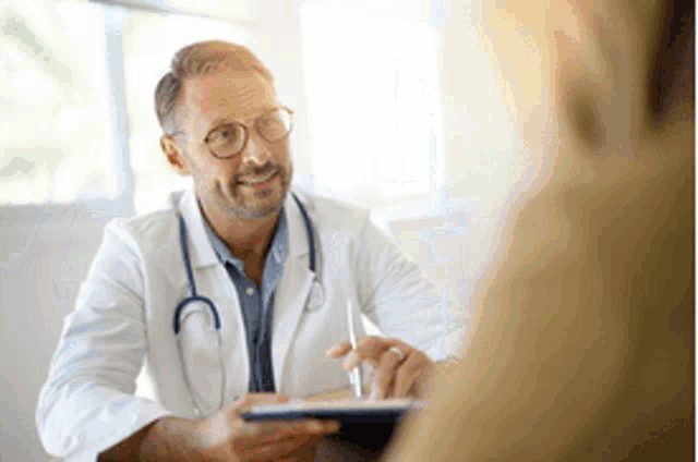 a doctor is talking to a patient in a hospital room while holding a tablet .
