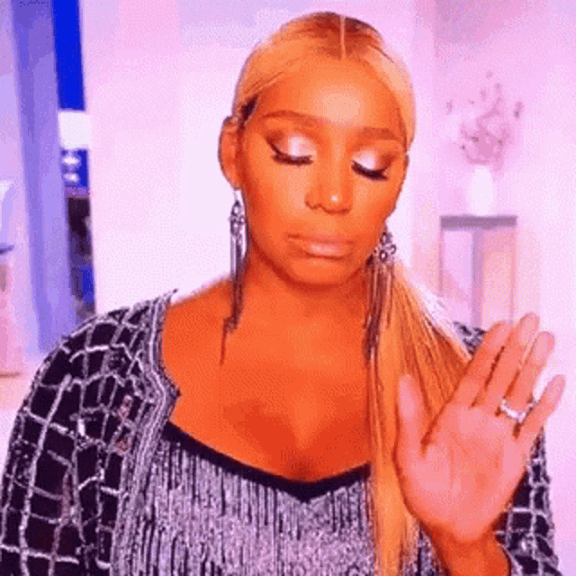 a woman with blonde hair is making a funny face while holding her hand up .