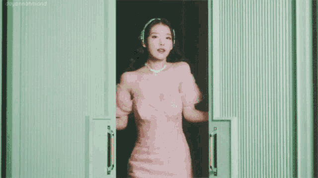 a woman in a pink dress stands in a doorway